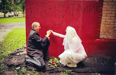 Brautpaar zeichnet Herz mit Pfeil an Wand 